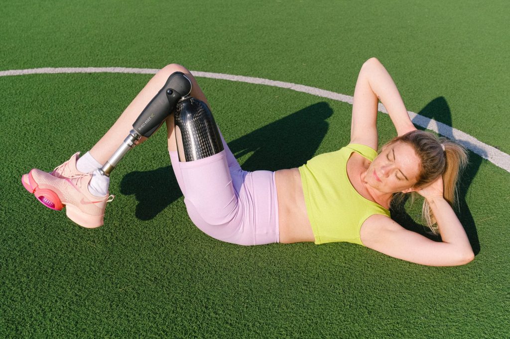 fit woman with leg prosthesis training on stadium